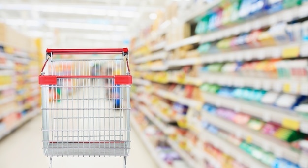 Navata laterale del supermercato con il carrello rosso vuoto