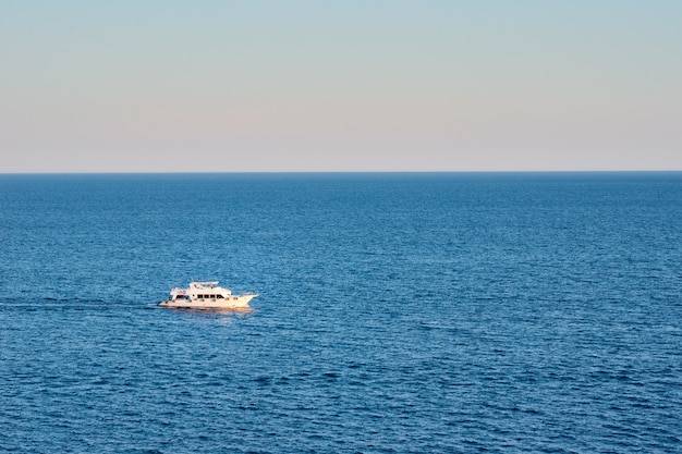 Nave bianca in mare o oceano contro il tramonto