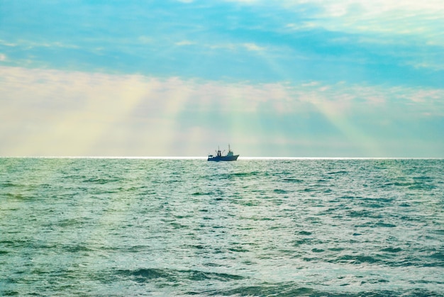 Nave contro il tramonto sul mare. Paesaggio marino colorato con i raggi del sole.