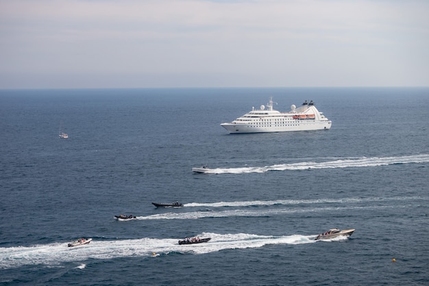 Nave da crociera del passeggero in mare durante la giornata di sole circondata da un sacco di motoscafi. Monte Carlo, Monaco.