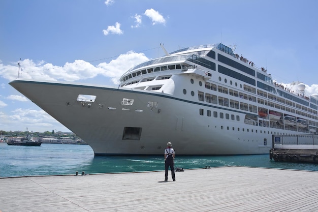 Nave da crociera turistica in porto con turisti a bordo e un marinaio