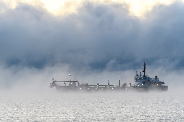 Nave impegnata nel dragaggio Draga al lavoro in mare Forte nebbia nel mare Artico