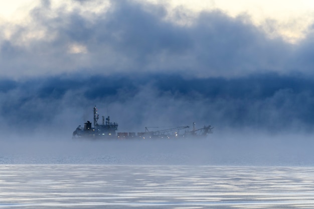 Nave impegnata nel dragaggio Draga al lavoro in mare Forte nebbia nel mare Artico