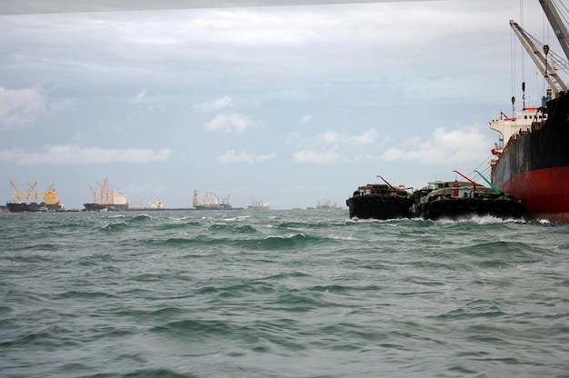 Nave mercantile galleggiante nell'oceano mare coda di attesa per il trasferimento di merci mentre tempesta di vento piovosa sera al tramonto tra Koh Loy e l'isola di Ko Sichang nella città di Sriracha a Chonburi Thailandia