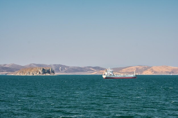 Nave nel mare turchese sullo sfondo delle coste autunnali