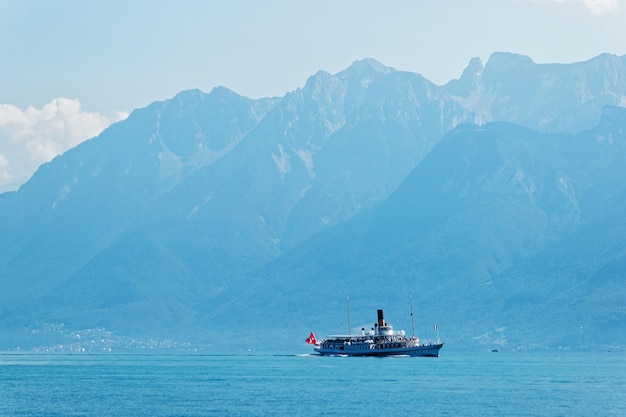Nave traghetto con bandiera svizzera, nel lago di Ginevra presso l'argine di Ouchy a Losanna, Svizzera. Persone a bordo