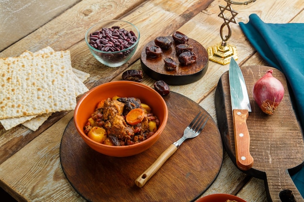Navetta ebraica per piatti con carne in un piatto su un tavolo di legno accanto al pane azzimo. Forchetta e ingredienti.