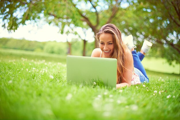 Navigando all'esterno in una bella giornata Scatto di una giovane donna che usa il suo laptop al parco