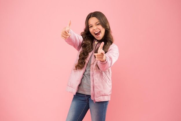 Ne hai bisogno per l'autunno Bambino felice mostra pistole sfondo rosa Bambina con look autunnale Stile autunnale casual Abito autunnale alla moda Tendenze moda per bambini Mantenersi attivi in autunno