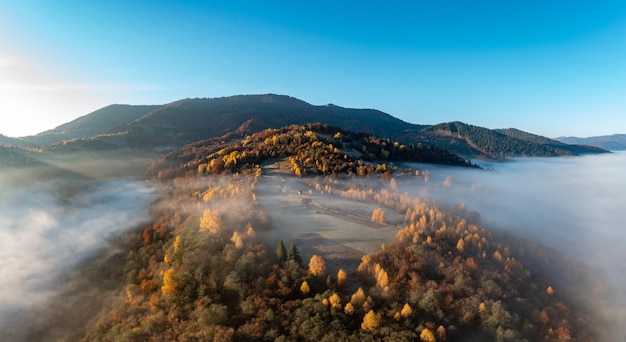 Nebbia fitta tra le cime delle alte montagne autunnali all'alba