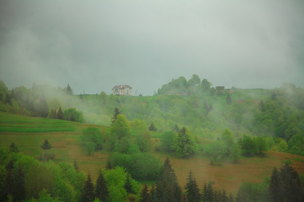 Nebbia mattutina Paesaggio di montagna con casa solitaria sullo sfondo