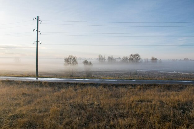 Nebbia sulla strada lungo il campo all'alba nebbia nel campo autunnale lungo l'autostrada Ulyanovsk