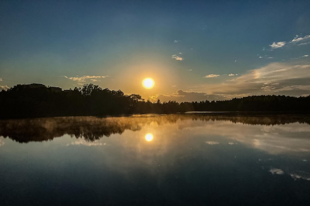 Nebbia sulla superficie dell'acqua del lago al tramonto in estate