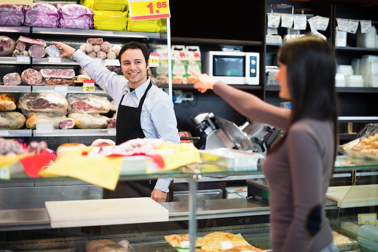 Foto negoziante al servizio di un cliente nel suo negozio di alimentari