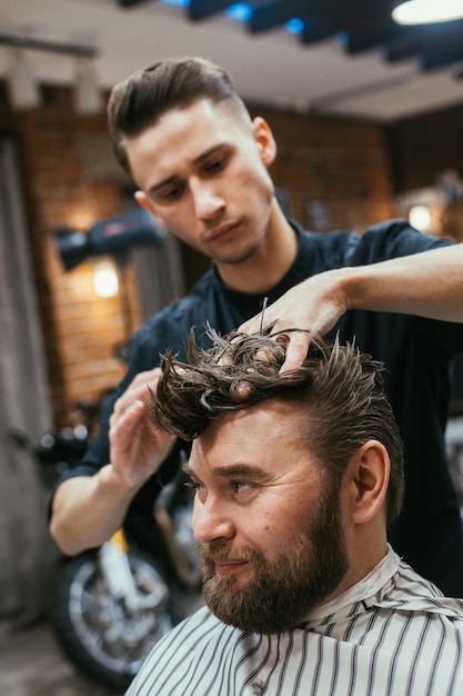 Negozio di barbiere, un uomo con un parrucchiere taglio barba. Bei capelli e cura, parrucchiere per uomo. Taglio di capelli professionale, acconciatura retrò e styling. Assistenza clienti. Russia, Sverdlovsk, 12 febbraio 2018