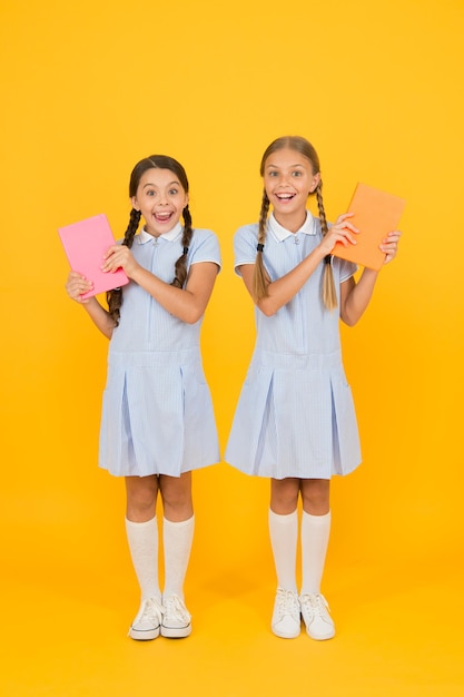 Negozio di libri concetto vintage kid moda torna a scuola piccole ragazze tenere cartella di lavoro e blocco note enciclopedia libro per bambini piccole ragazze amano leggere vecchia scuola sorpresi amici in uniforme retrò