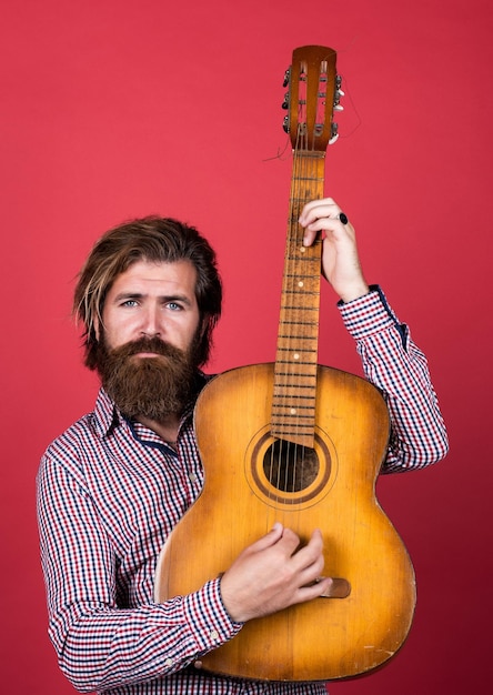 Negozio di musica vintage uomo barbuto che è un chitarrista maschio casual rock star concetto di musica e uomo vocale che suona la chitarra acustica uomo brutale con baffi e barba che tengono la chitarra