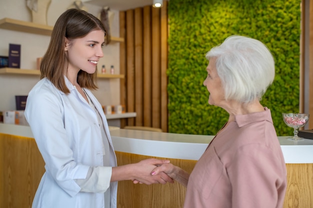 Nel centro estetico. Donna matura che incontra un cosmetologo in un centro di bellezza