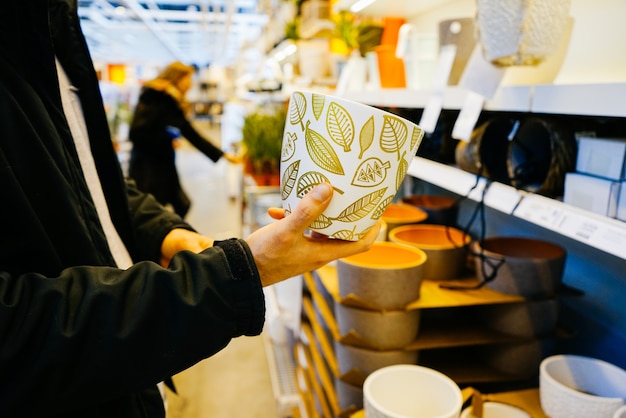 Nel negozio di ferramenta un uomo tiene in mano un insolito vaso di fiori