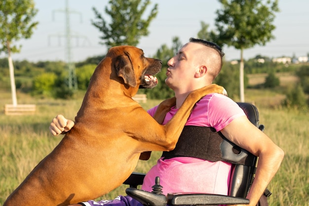 Nel parco un giovane in sedia a rotelle si occupa di attività giocose con il suo cane