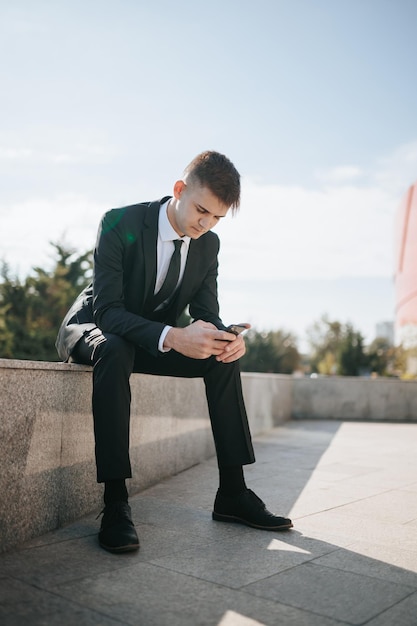 Nel quartiere degli affari urbano, un giovane uomo d'affari caucasico americano siede intensamente vestito con un abito tagliente