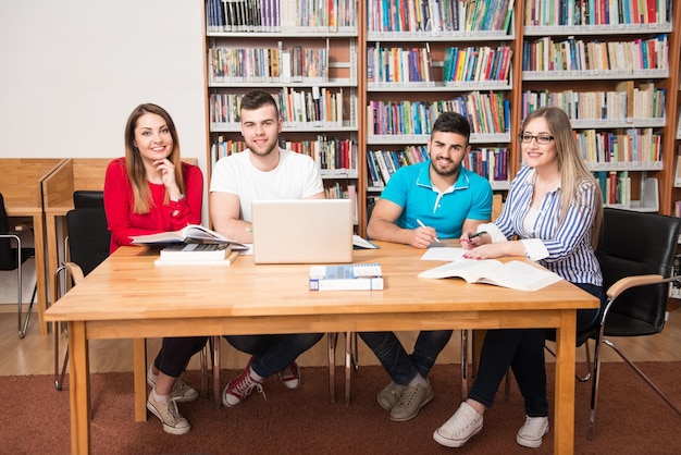 Nella biblioteca Bel gruppo di studenti con laptop e libri che lavorano in una biblioteca universitaria di scuola superiore Profondità di campo ridotta