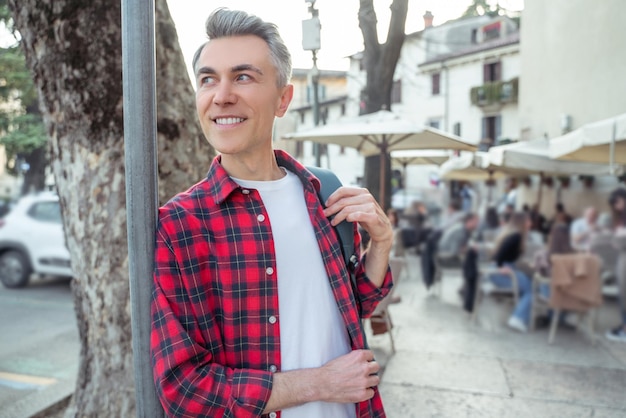 Nella strada. Uomo sorridente in camicia a quadri nella via della città