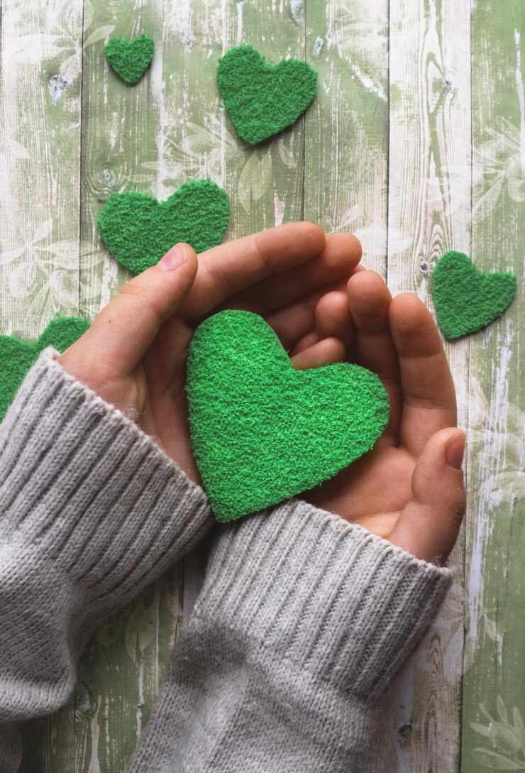 Foto nelle mani di un cuore verde carta su sfondo chiaro