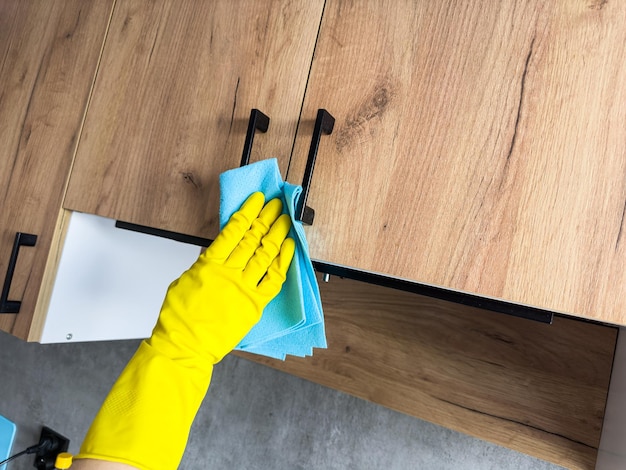 Nelle vicinanze una casalinga con i guanti gialli che lava il tavolo di legno in cucina.