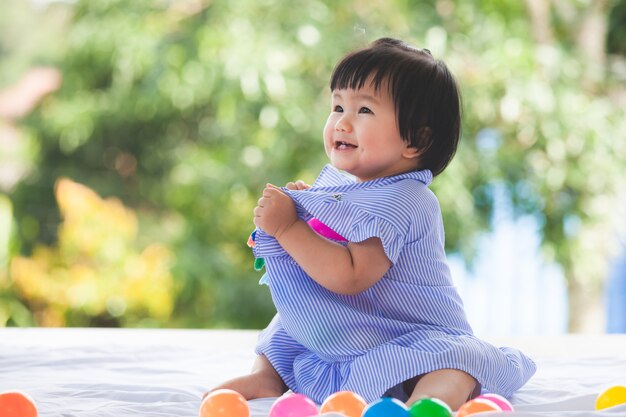 Neonata asiatica sveglia che gioca con il suo giocattolo con felicità