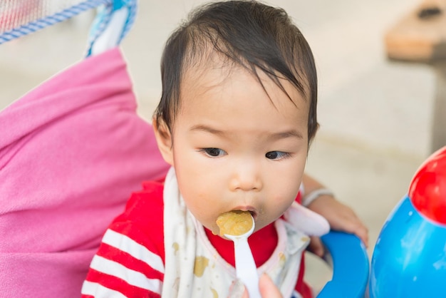 Neonata asiatica sveglia che mangia riso con la gente di momThailand Tempo per gli alimenti