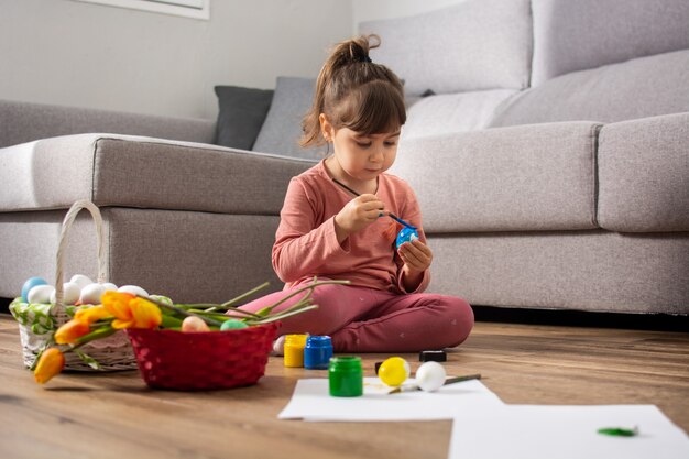 Neonata che dipinge le uova di Pasqua a casa.