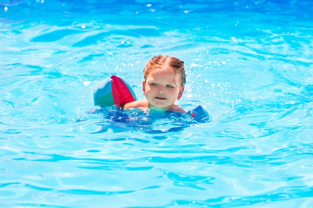 Neonata che nuota in piscina con maniche galleggianti