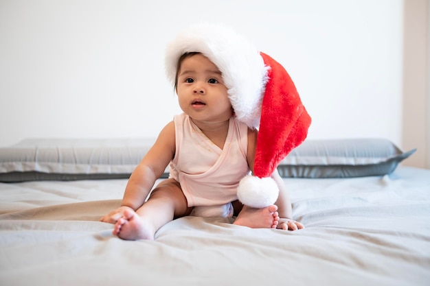 Neonata che ride indossando il cappello di Babbo Natale a casa