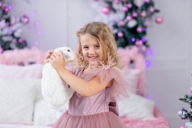 Neonata con coniglio all'albero di Natale in un bellissimo vestito rosa