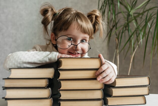 Neonata divertente felice in vetri che leggono un libro. Ragazza emotiva. A scuola presto. Copia spazio.