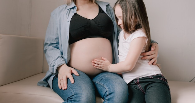 Neonata e madre incinta amorevole sorellina accanto alla pancia della madre. famiglia felice