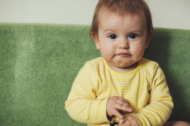 Neonata in buona salute che si siede sul sofà che fa lo stile di vita sano della famiglia abbastanza giovane dell'espressione facciale