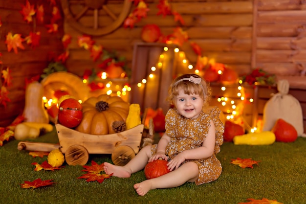 Neonata in decorazioni autunnali con zucche, bacche e foglie per il ringraziamento o halloween