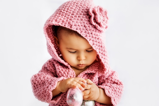 Neonata in pagliaccetto rosa che gioca con le uova di Pasqua, concetto di festa di stagione