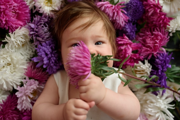 Neonata in vestito bianco che gioca con il mazzo di fiori