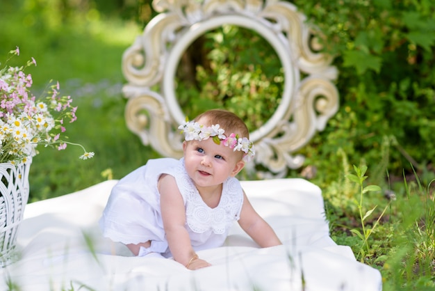 Neonata in vestito bianco in un giardino di primavera con fiori