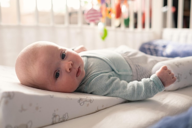 Neonata sveglia che esamina macchina fotografica che riposa nel letto