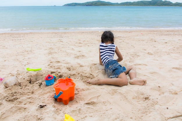 Neonata sveglia che gioca con i giocattoli della spiaggia