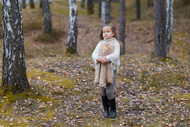 Neonata sveglia che tiene le baguette in un parco di autunno in una giornata calda