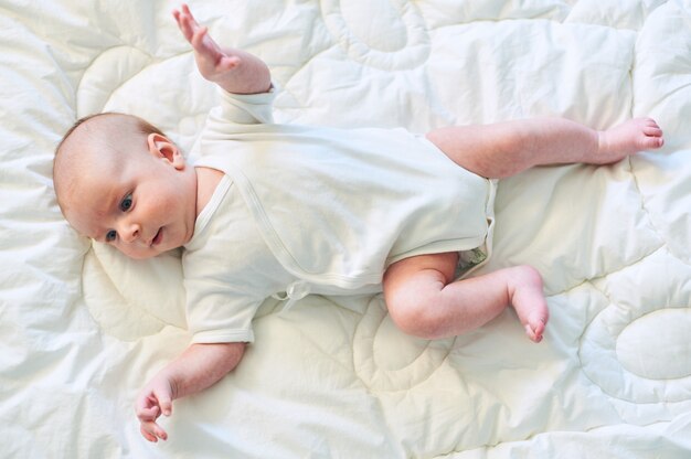 Neonato adorabile in camera da letto soleggiata bianca. Bambino neonato che si rilassa a letto.