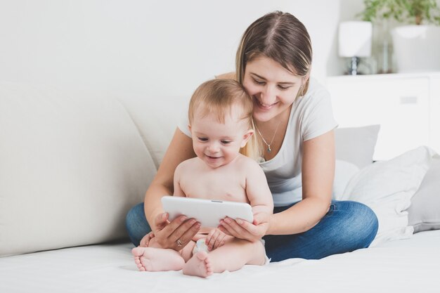 Neonato allegro felice che gioca sul tablet PC con la madre