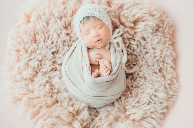 Neonato asiatico con il sonno tricottato del cappello
