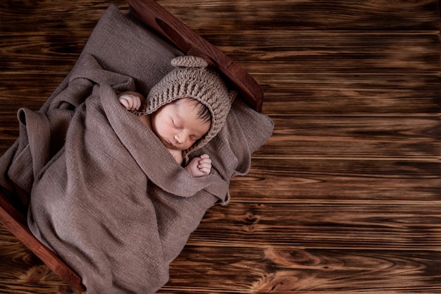 Neonato, bellissimo bambino si trova in una coperta di pelliccia marrone su fondo di legno