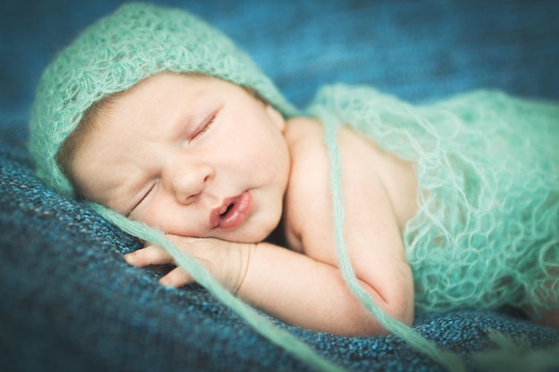 Neonato che dorme dolcemente su un tappeto blu con cappuccio blu